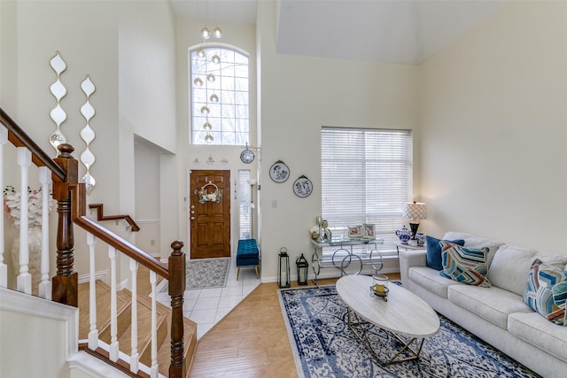 foyer entrance with a towering ceiling, baseboards, stairway, and light tile patterned flooring