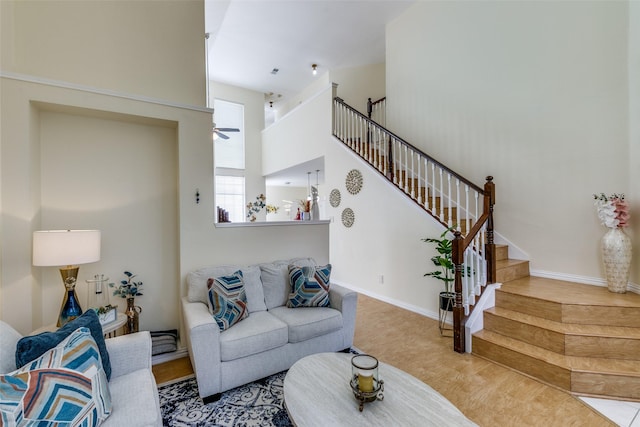 living area featuring baseboards, a high ceiling, stairway, and wood finished floors