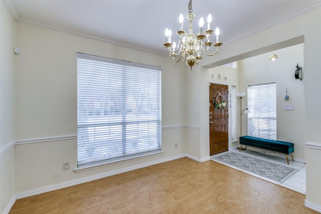 entrance foyer featuring baseboards, ornamental molding, a chandelier, and wood finished floors