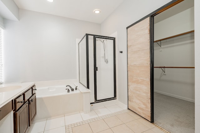 bathroom with a stall shower, a walk in closet, a garden tub, and tile patterned floors