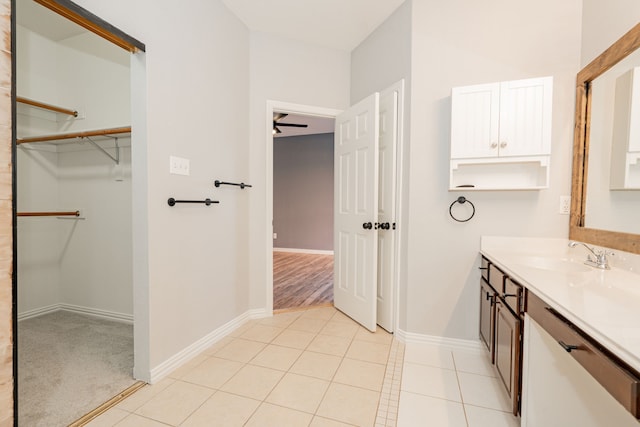 bathroom featuring a walk in closet, vanity, baseboards, and tile patterned floors