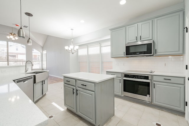 kitchen featuring gray cabinetry, stainless steel appliances, a kitchen island, a sink, and decorative backsplash