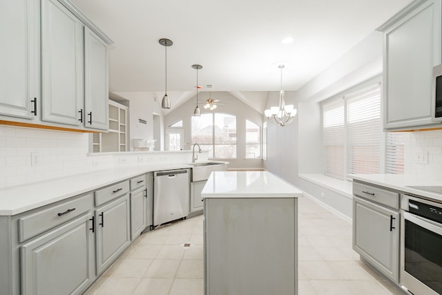 kitchen with gray cabinetry, a peninsula, a kitchen island, a sink, and appliances with stainless steel finishes