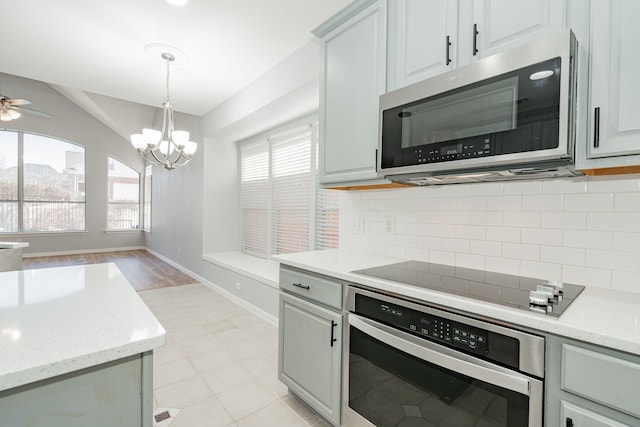 kitchen with stainless steel appliances, hanging light fixtures, a wealth of natural light, and decorative backsplash