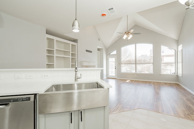 kitchen featuring lofted ceiling, open floor plan, light countertops, stainless steel dishwasher, and a sink