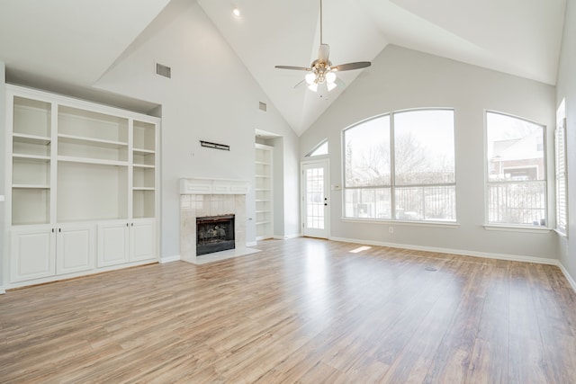 unfurnished living room featuring built in shelves, visible vents, a ceiling fan, light wood-type flooring, and a tile fireplace