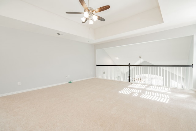 spare room featuring ceiling fan, carpet flooring, visible vents, baseboards, and a raised ceiling