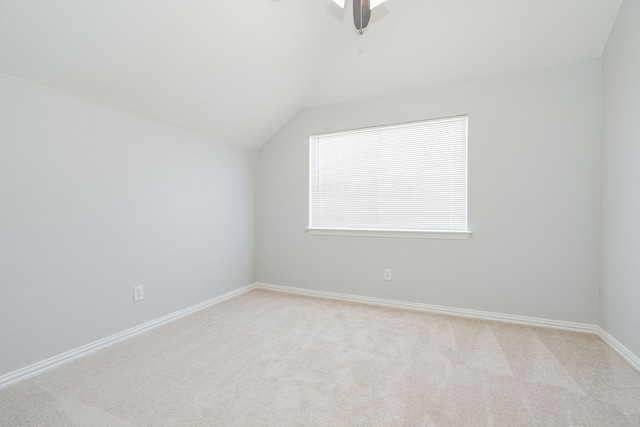 spare room featuring lofted ceiling, baseboards, and light colored carpet