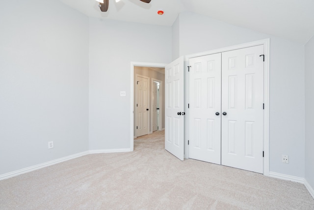 unfurnished bedroom featuring baseboards, vaulted ceiling, and light colored carpet