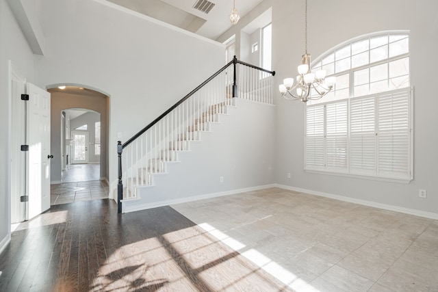 interior space featuring stairway, a chandelier, arched walkways, a high ceiling, and visible vents