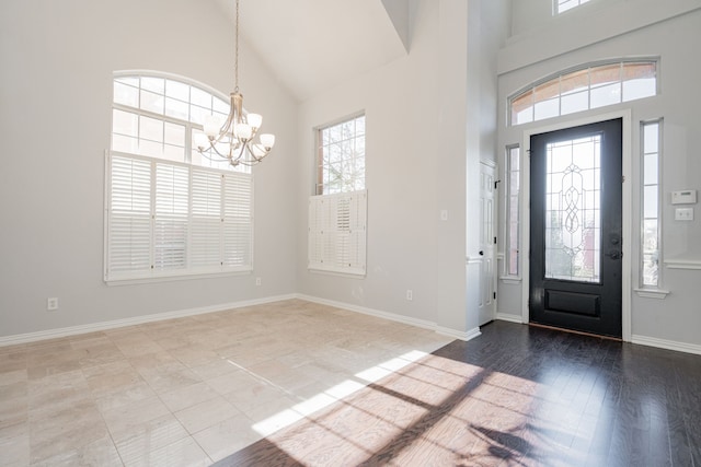 foyer entrance featuring high vaulted ceiling, baseboards, a chandelier, and wood finished floors