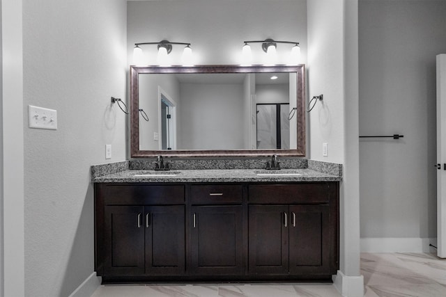 full bath with marble finish floor, a sink, baseboards, and double vanity