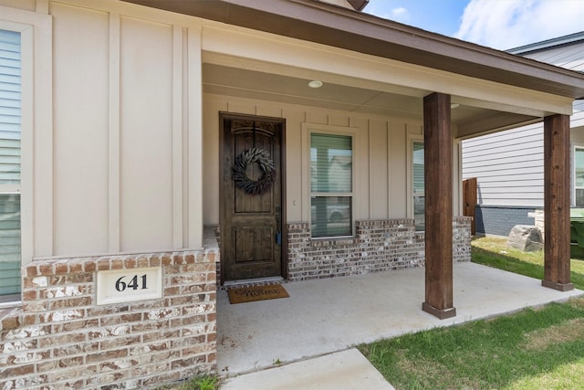 property entrance featuring brick siding and a porch