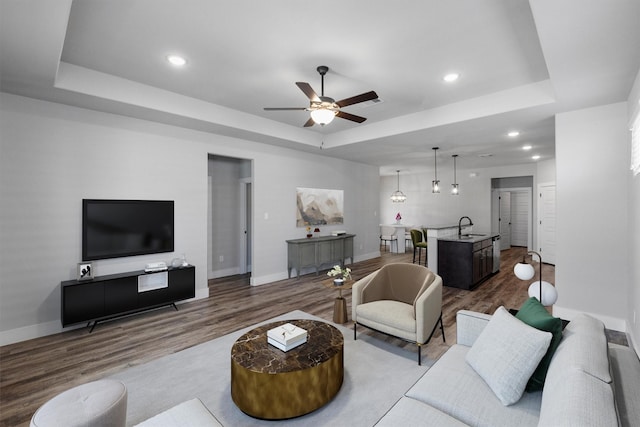 living room with recessed lighting, a raised ceiling, dark wood-type flooring, ceiling fan, and baseboards