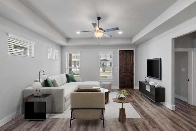 living room with baseboards, a tray ceiling, wood finished floors, and recessed lighting