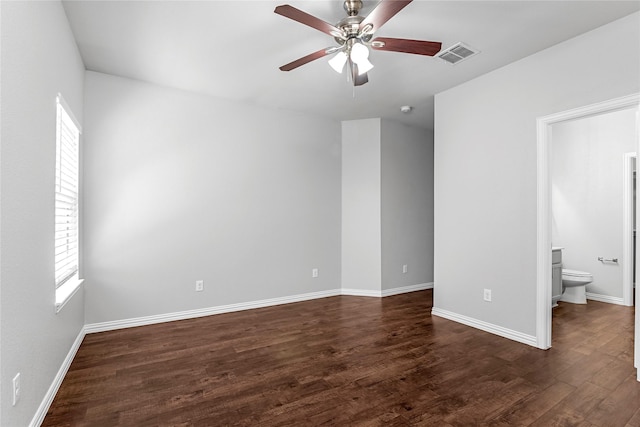 unfurnished bedroom featuring ensuite bathroom, dark wood-style flooring, a ceiling fan, visible vents, and baseboards