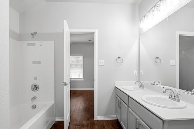 bathroom featuring double vanity, a sink, baseboards, and wood finished floors