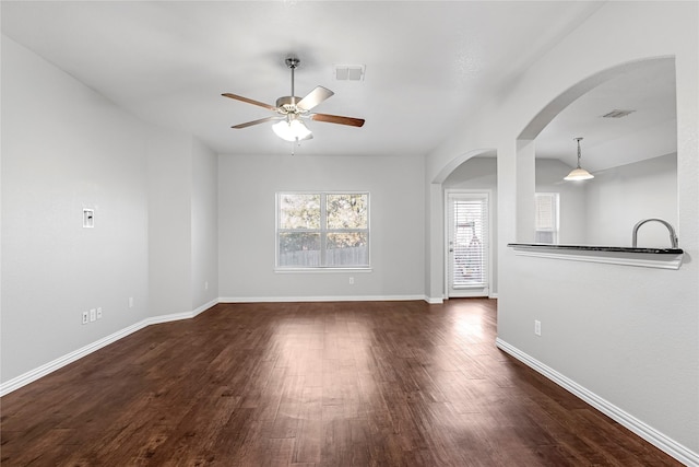 unfurnished living room featuring baseboards, visible vents, ceiling fan, and dark wood-type flooring