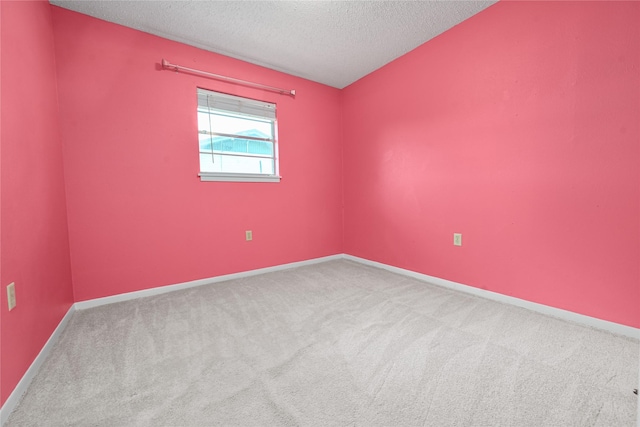 spare room with a textured ceiling, carpet floors, and baseboards