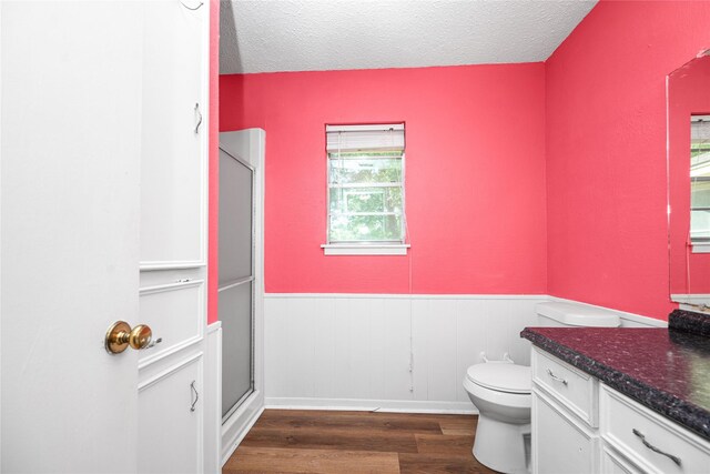 full bath with wood finished floors, wainscoting, a shower stall, vanity, and toilet