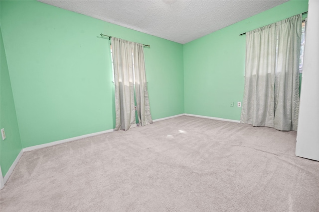 spare room with a textured ceiling, carpet flooring, and baseboards