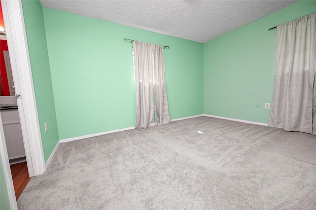 unfurnished room featuring a textured ceiling, carpet floors, and baseboards