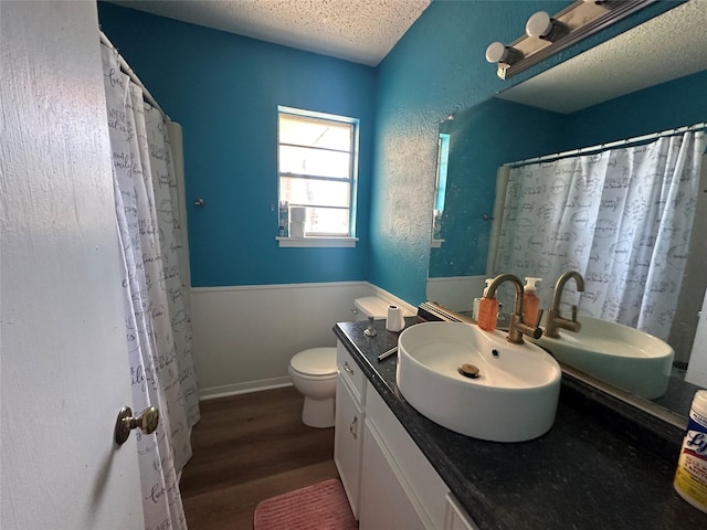 bathroom with curtained shower, toilet, a textured ceiling, vanity, and wood finished floors