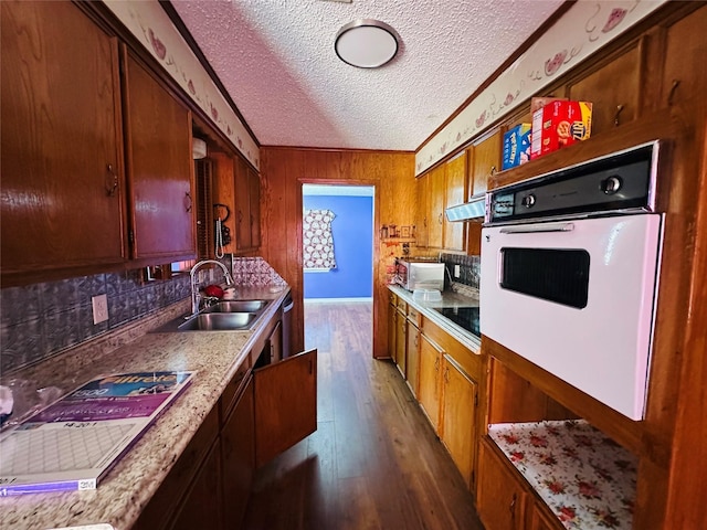 kitchen featuring dark wood finished floors, oven, black electric stovetop, a textured ceiling, and a sink