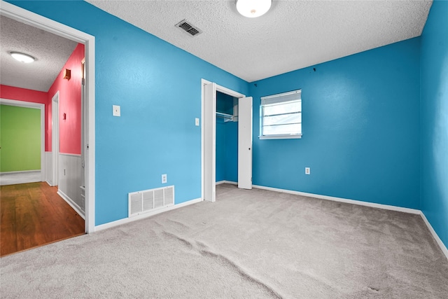 unfurnished bedroom with a textured ceiling, carpet, a closet, and baseboards