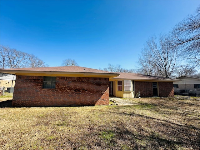 rear view of house featuring a yard, fence, and brick siding