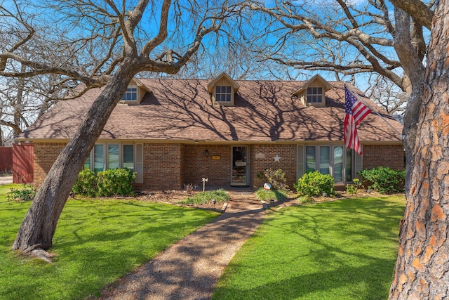 view of front of house with brick siding, a front lawn, and a shingled roof