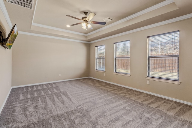 empty room featuring ornamental molding, a raised ceiling, visible vents, and carpet flooring