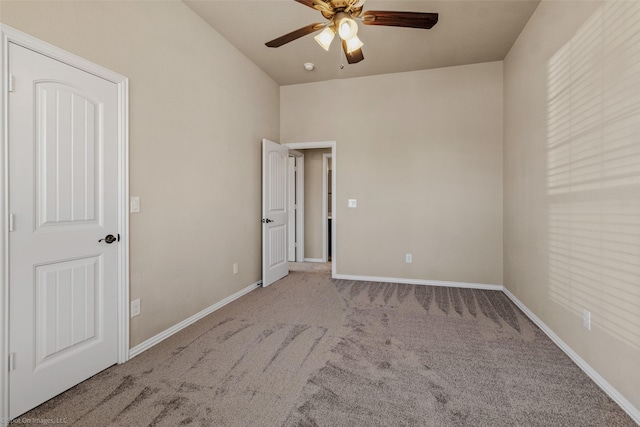 carpeted spare room featuring a ceiling fan and baseboards