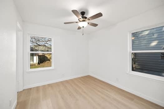 unfurnished room with light wood finished floors, baseboards, and a ceiling fan