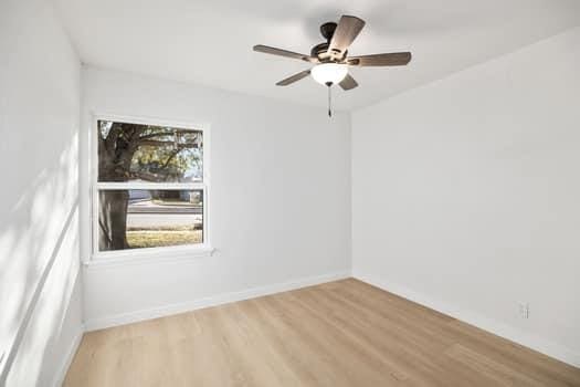 spare room with light wood finished floors, ceiling fan, and baseboards