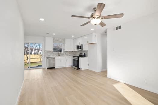 kitchen with stainless steel appliances, light countertops, decorative backsplash, light wood-style floors, and white cabinets