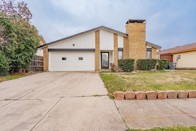 mid-century modern home with brick siding, a chimney, fence, a garage, and driveway