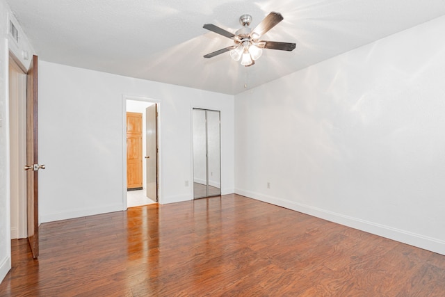 unfurnished bedroom with a closet, wood finished floors, a ceiling fan, and baseboards