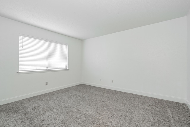 unfurnished room featuring carpet floors and baseboards