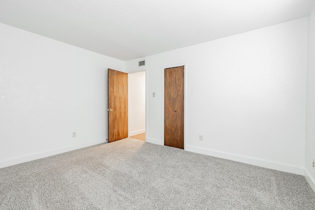 empty room featuring carpet, visible vents, and baseboards