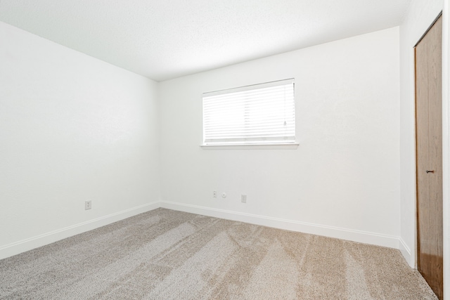 carpeted spare room featuring baseboards