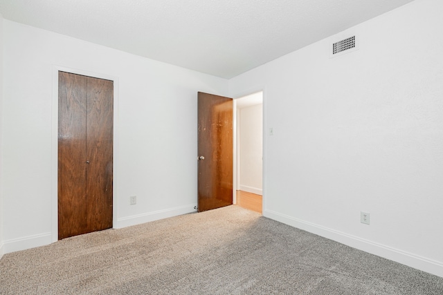 unfurnished bedroom with carpet floors, a closet, visible vents, and baseboards