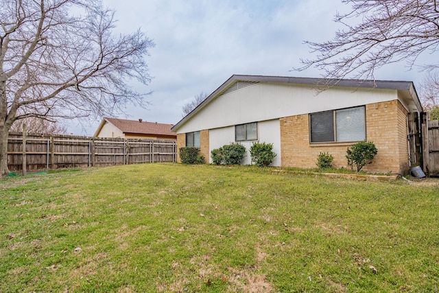 exterior space featuring brick siding, a lawn, and a fenced backyard