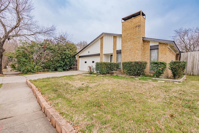 view of home's exterior featuring an attached garage, fence, driveway, a yard, and a chimney