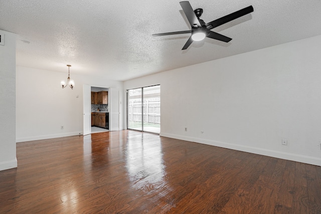 spare room featuring ceiling fan with notable chandelier, dark wood-type flooring, and baseboards