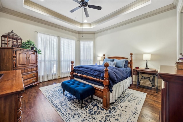 bedroom with a tray ceiling, dark wood-style flooring, a ceiling fan, and crown molding