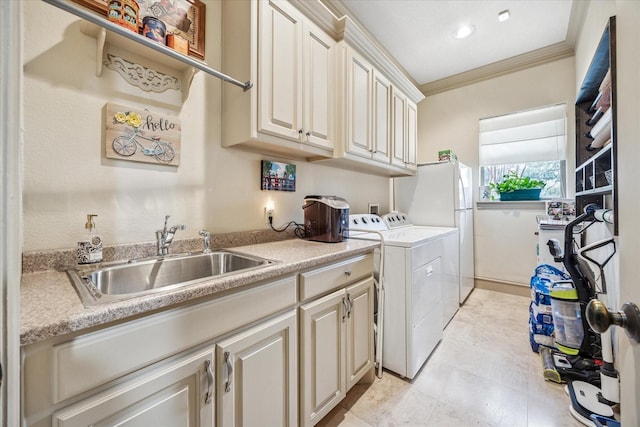 clothes washing area with crown molding, washing machine and dryer, cabinet space, and a sink