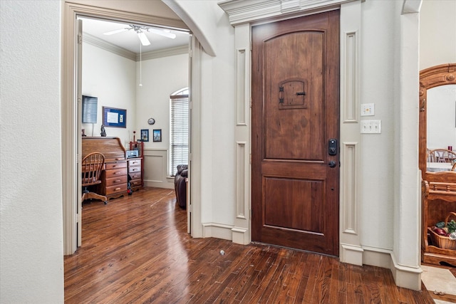 foyer entrance with dark wood-style floors, ornamental molding, arched walkways, and a ceiling fan