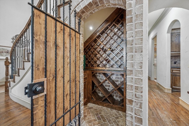 wine cellar featuring arched walkways and wood finished floors