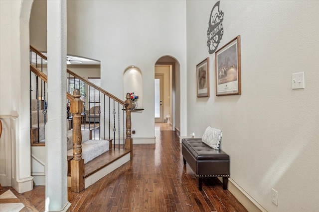 entryway featuring arched walkways, a towering ceiling, baseboards, stairway, and hardwood / wood-style floors